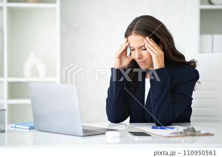 Stressed mature businesswoman sitting at workplace, suffering from headache Stressed mature businesswoman sitting at workplace, suffering from headache 110950561