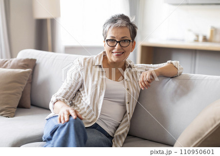 Portrait of beautiful senior woman relaxing on comfortable couch at home 110950601