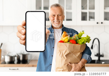 Happy Senior Man Demonstrating Blank Smartphone And Holding Bag With Groceries 110950777