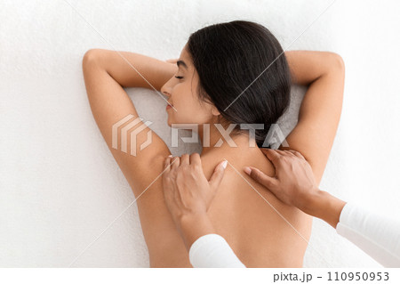 Top view beautiful young indian woman receiving relaxing shoulder massage Top view beautiful young indian woman receiving relaxing shoulder massage 110950953