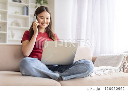 Remote Business. Asian Woman Talking On Phone And Using Laptop At Home 110950962