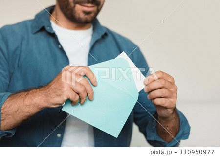Unrecognizable middle aged man opening envelope receiving a letter indoor Unrecognizable middle aged man opening envelope receiving a letter indoor 110950977