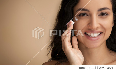 Millennial woman applying eye cream, copy space Millennial woman applying eye cream, copy space 110951054