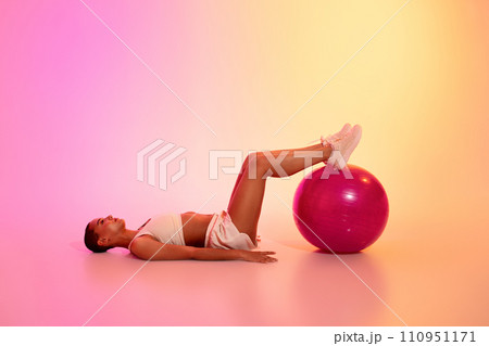 Focused slim young latina woman in sportswear lie, make exercises with fitness ball 110951171