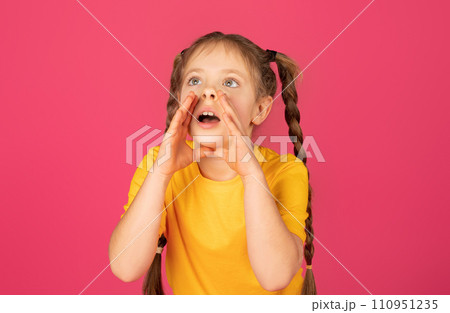 Cute little girl keeping hands near mouth and shouting at copy space 110951235