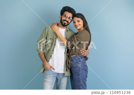 Beautiful millennial indian couple posing on blue studio background Beautiful millennial indian couple posing on blue studio background 110951236