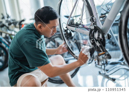 young man washing bicycle wheel rims at a bicycle shop 110951345