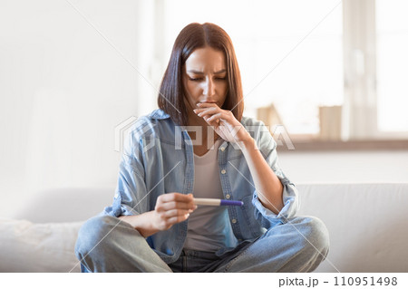 Upset disappointed young european lady holds negative pregnancy test indoor Upset disappointed young european lady holds negative pregnancy test indoor 110951498