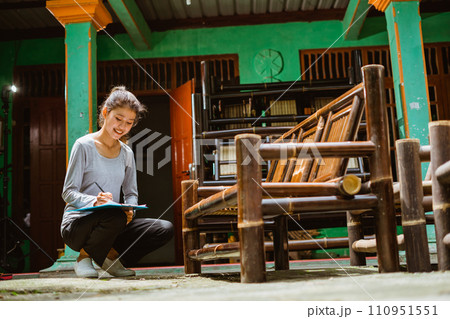 young Asian entrepreneur squatting while working with a clipboard 110951551