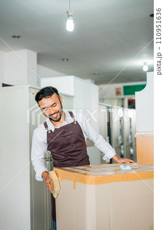 shop assistant man wrapping furniture using cardboard before sending it shop assistant man wrapping furniture using cardboard before sending it 110951636