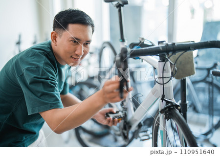 young Asian man seriously checks the pedals and handlebar young Asian man seriously checks the pedals and handlebar 110951640