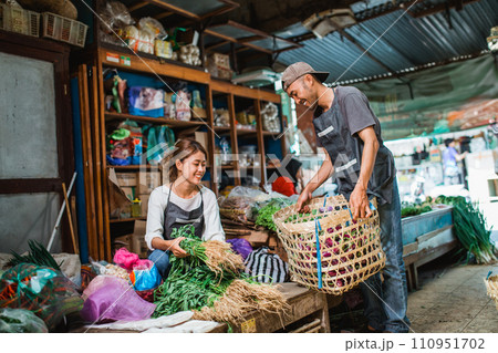 male seller helping female seller arranging vegetables 110951702