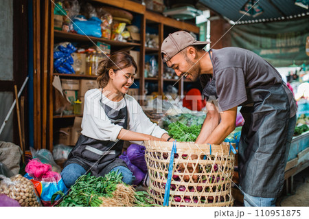 couple seller picking vegetables from basket 110951875