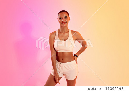 Glad slim young latin lady athlete in sportswear ready to workout on neon pink studio background Glad slim young latin lady athlete in sportswear ready to workout on neon pink studio background 110951924
