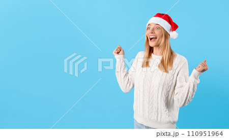 Excited woman in Santa hat celebrating clenching fists Excited woman in Santa hat celebrating clenching fists 110951964