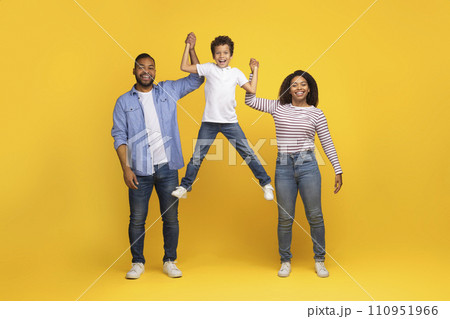 Cheerful Young Black Family Of Three Having Fun Together Over Yellow Background Cheerful Young Black Family Of Three Having Fun Together Over Yellow Background 110951966