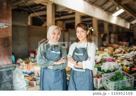 two female vegetable sellers standing with crossed arm two female vegetable sellers standing with crossed arm 110952109