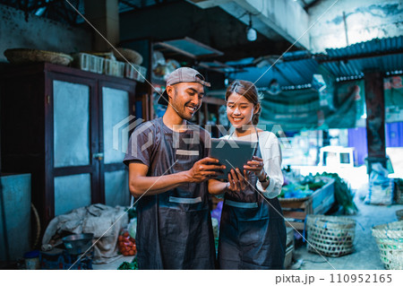 couple greengrocery sellers standing and holding tablet 110952165