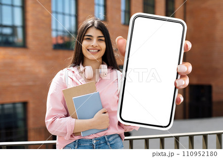 student woman holding books and huge smartphone blank touchscreen outdoors student woman holding books and huge smartphone blank touchscreen outdoors 110952180