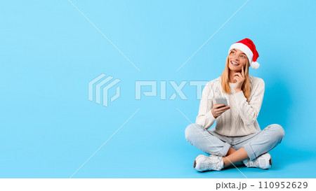 Thoughtful woman with phone in Santa hat Thoughtful woman with phone in Santa hat 110952629