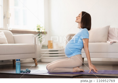 pregnant woman doing backbend during yoga workout at home 110952769