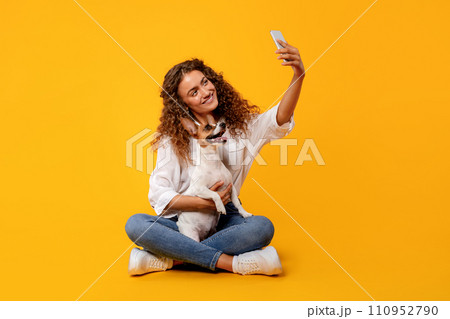 Woman and dog take selfie on yellow background Woman and dog take selfie on yellow background 110952790