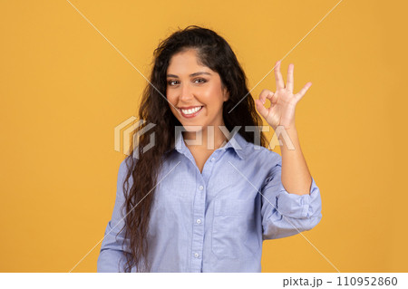Smiling latin millennial brunette lady in casual show ok sign with hand, recommend sale 110952860