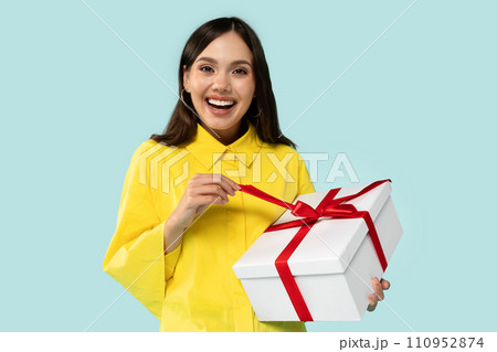Positive cheerful young brunette lady holding wrapped gift box 110952874
