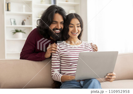 Positive young indian couple have video call with friends Positive young indian couple have video call with friends 110952958