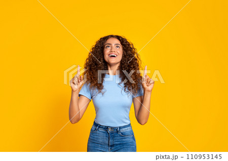 Joyful woman pointing up on a yellow background Joyful woman pointing up on a yellow background 110953145