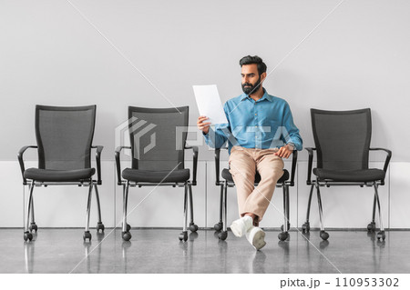 Indian man analyzing document in job interview waiting room 110953302