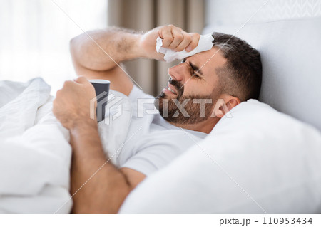 Sick Man Drinking Tea While Lying In Modern Bedroom 110953434