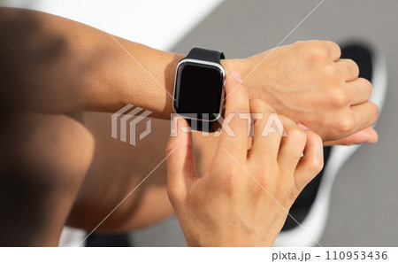 Cropped shot of fitness guy taps smartwatch on wrist, studio 110953436