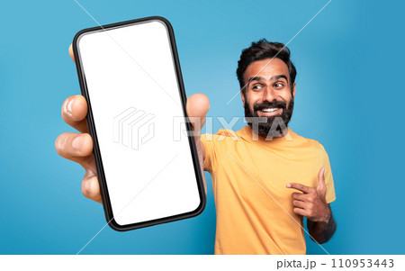 Middle Eastern man pointing at large smartphone screen, blue background Middle Eastern man pointing at large smartphone screen, blue background 110953443