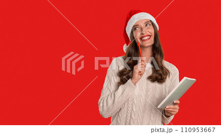 woman in Santa hat writes holiday wishlist in notebook, studio woman in Santa hat writes holiday wishlist in notebook, studio 110953667