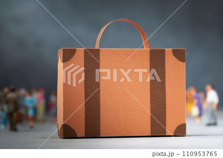 Cardboard suitcase and out of focus plastic toy men on an abstract background, concept on the theme of moving or migration, template for designer 110953765
