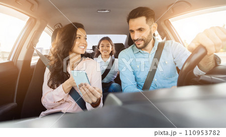 Family enjoying a car ride with mother holding a phone and child smiling in the back Family enjoying a car ride with mother holding a phone and child smiling in the back 110953782