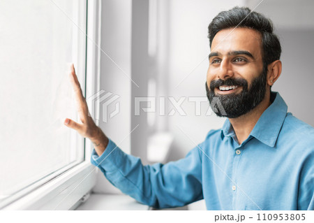 Happy indian businessman smiling by the window Happy indian businessman smiling by the window 110953805