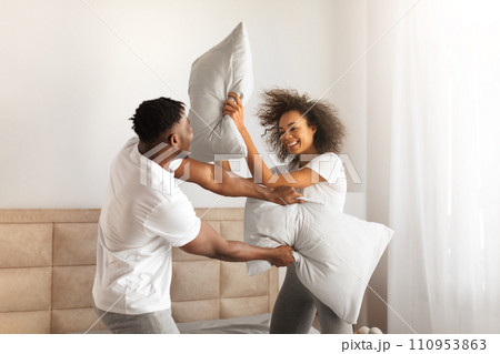 Joyful African Couple Having Pillow Fight For Fun In Bedroom Joyful African Couple Having Pillow Fight For Fun In Bedroom 110953863