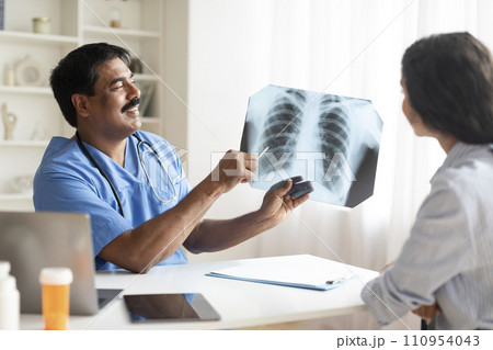 Indian Doctor Man Demonstrating Chest X-Ray To Female Patient In Clinic 110954043