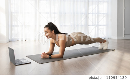 Young woman have workout at home, using laptop 110954129