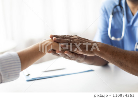 Closeup Of Doctor Holding Hand Of Female Patient During Meeting In Office Closeup Of Doctor Holding Hand Of Female Patient During Meeting In Office 110954263