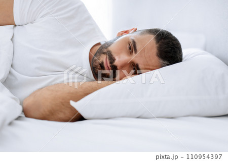 Middle aged bearded man struggles with insomnia lying in bedroom Middle aged bearded man struggles with insomnia lying in bedroom 110954397