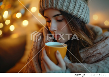 A cozy and comforting scene of a woman in a woolen hat, wrapped in a warm blanket, sitting in a living room and sipping tea, the ambiance is homely and relaxing A cozy and comforting scene of a woman in a woolen hat, wrapped in a warm blanket, sitting in a living room and sipping tea, the ambiance is homely and relaxing 110954570