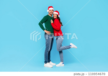 Happy european spouses in Santa hats hugging on blue background Happy european spouses in Santa hats hugging on blue background 110954670