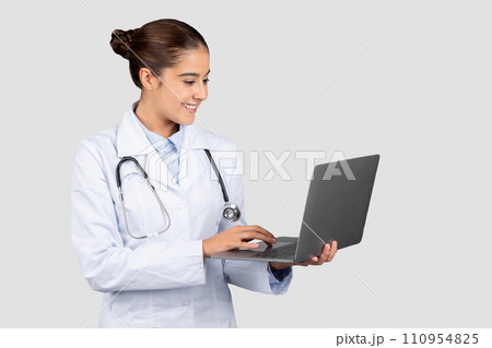 Positive millennial european lady doctor typing on computer, chatting with patient Positive millennial european lady doctor typing on computer, chatting with patient 110954825