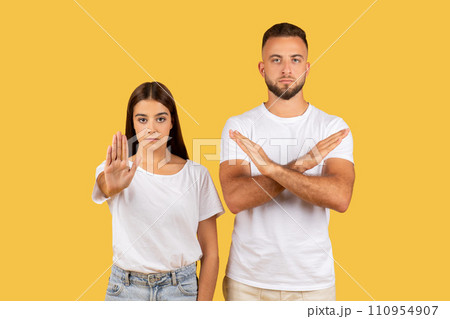 Angry strict millennial european man and lady in white t-shirts make stop gesture with hand 110954907