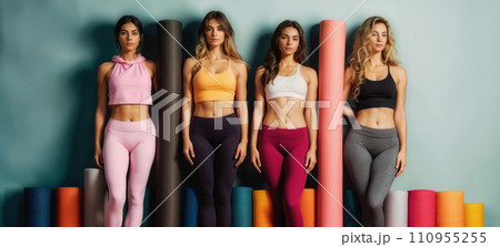 A group of women in sportswear stand in front of yoga mats in a variety of colors. A group of women in sportswear stand in front of yoga mats in a variety of colors. 110955255