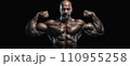A muscular man poses shirtless in front of a black background, flexing his muscles. 110955258
