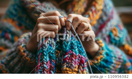 Woman knits a sweater from multi-colored threads 110956382